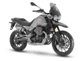 Srebrny motocykl Moto Guzzi V85 TT z czarnym siedzeniem i przyciemnianą szybą, gotowy na przygodę.