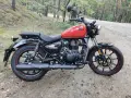 Czerwony Royal Enfield Meteor 350 na leśnej drodze. Klasyczny wygląd i nowoczesna technologia w jednym.