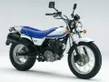 Biały Suzuki Van Van 125 z niebieskim siedzeniem i zielono-niebieskimi paskami na baku. Idealny na miejskie przygody.