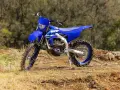 Niebieski motocykl Yamaha WR250F na tle leśnym. Szczegółowe yamaha wr 250 f dane techniczne dostępne dla miłośników off-roadu.
