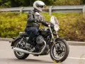 Motocyklista w kasku i skórzanej kurtce jedzie na stylowym motocyklu Moto Guzzi V9.