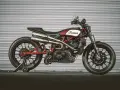 Stylowy Indian FTR 1200 w kolorze czerwono-białym, z podwójnym wydechem i czarnymi felgami, gotowy do jazdy.