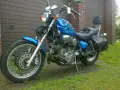 Błękitny motocykl Yamaha Virago 1100 z płomieniami, skórzanymi sakwami i oparciem. Wady i zalety tego klasyka do rozważenia przed zakupem.