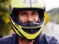 Uśmiechnięty mężczyzna w żółtym kasku motocyklowym z czarnymi elementami.