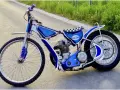 Niebieski motor żużlowy na asfalcie. Zastanawiasz się, ile kosztuje motor żużlowy? Ten wygląda na gotowy do startu!