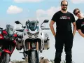 Dwóch mężczyzn w koszulkach 1000PS obok motocykli Honda Africa Twin.