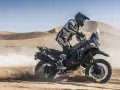 Motocyklista w pełnym rynsztunku szaleje na pustyni na swoim KTM 790 Adventure, wzbijając tumany piasku.
