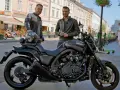 Dwóch mężczyzn pozuje obok czarnego motocykla Yamaha V-Max 1700 na ulicy.