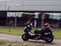 Elegancki skuter Honda Forza 300 zaparkowany przed budynkiem z napisem "Warszawa". Czerwony kask leży na siedzeniu.
