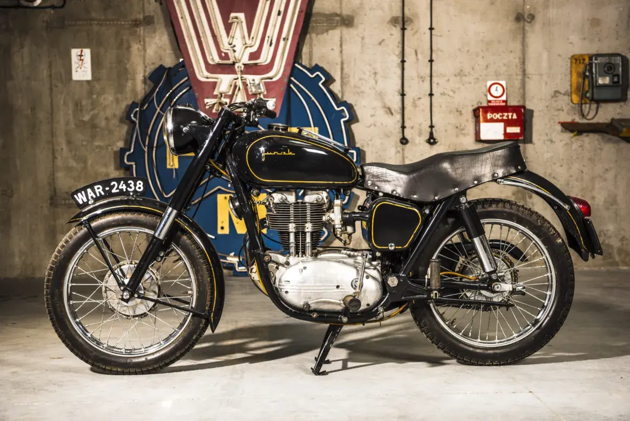 Czarny motocykl Junak, który produkuje polska fabryka, z żółtymi wstawkami i tablicą rejestracyjną WAR-2438.