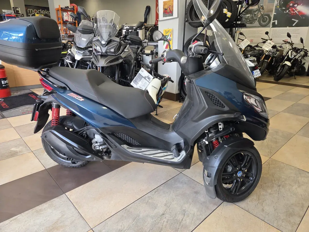 Trójkołowy skuter Piaggio MP3 300 w salonie. Sprawdź piaggio mp3 300 dane techniczne, by poznać jego możliwości.
