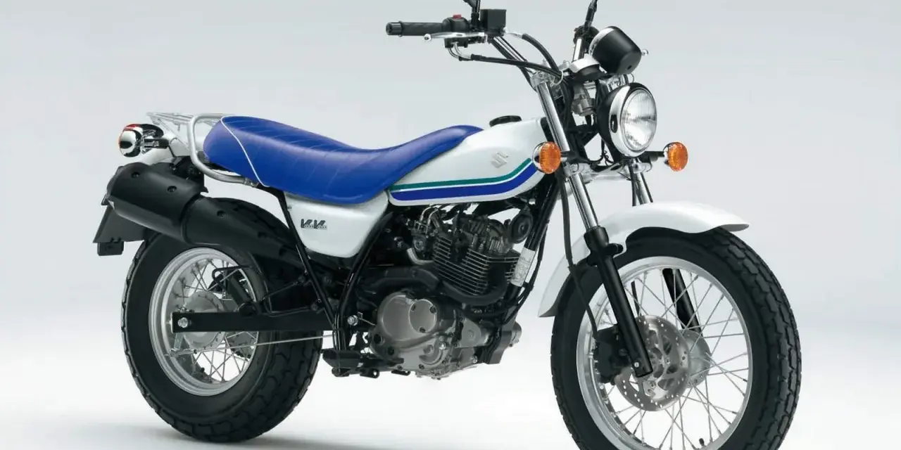Biały Suzuki Van Van 125 z niebieskim siedzeniem i zielono-niebieskimi paskami na baku. Idealny na miejskie przygody.
