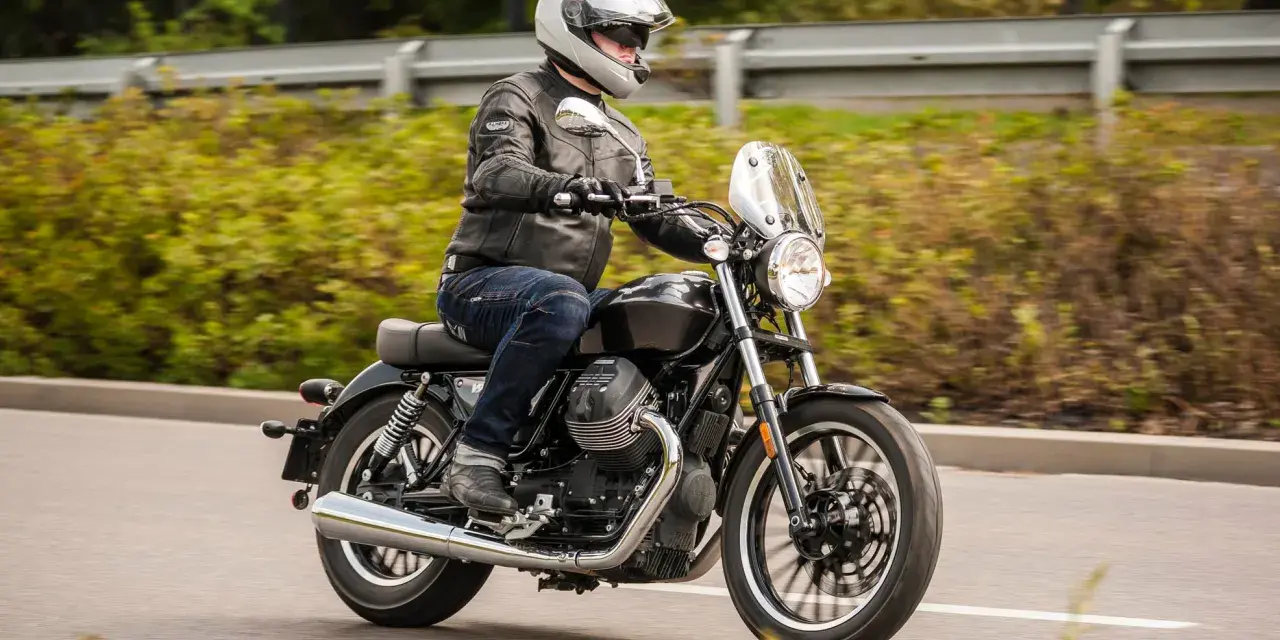 Motocyklista w kasku i skórzanej kurtce jedzie na stylowym motocyklu Moto Guzzi V9.