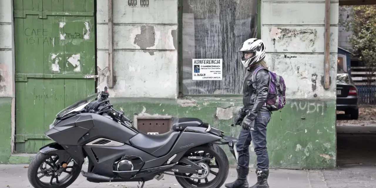 Motocyklista w kasku obok swojego futurystycznego Honda NM4 Vultus.