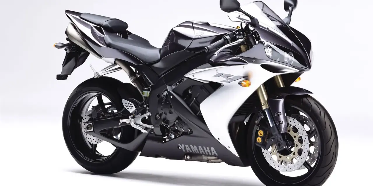 Sportowy motocykl Yamaha R1, jedna z wielu generacji, w kolorze czarno-białym, prezentuje się dynamicznie na białym tle.