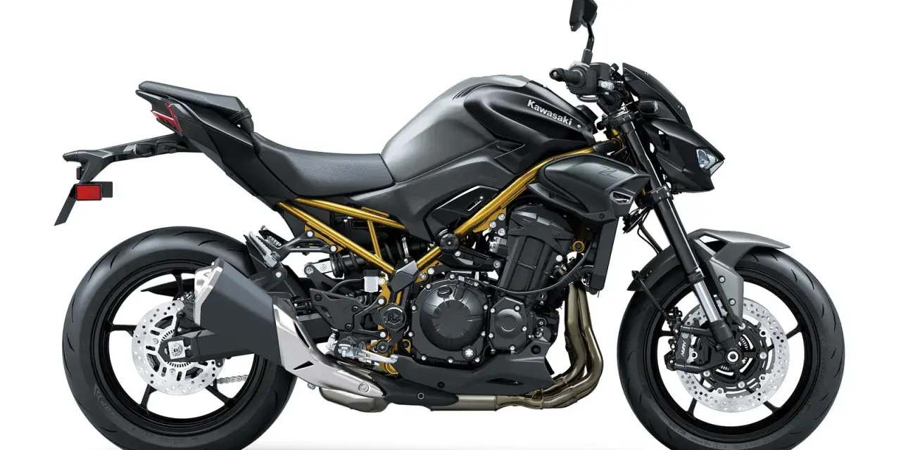 Stylowy, czarny Kawasaki Z900 z widoczną złotą ramą, gotowy na podbój dróg.