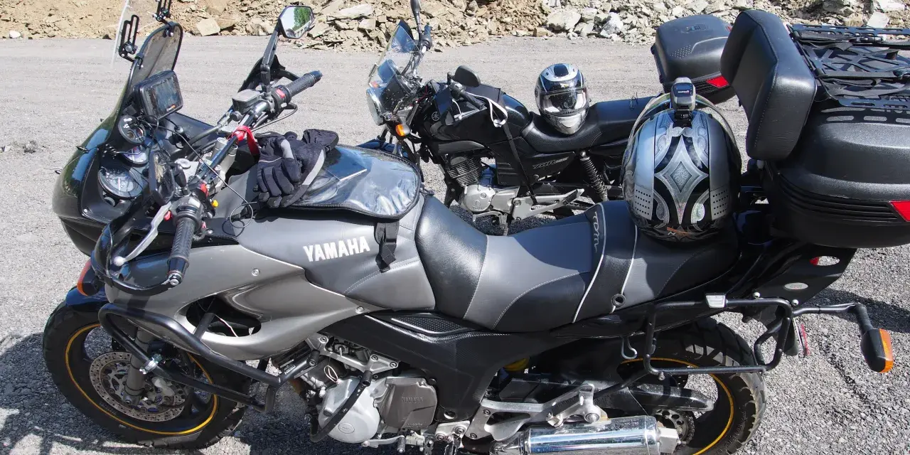 Dwa motocykle Yamaha zaparkowane na drodze szutrowej, jeden z kaskiem na siedzeniu.