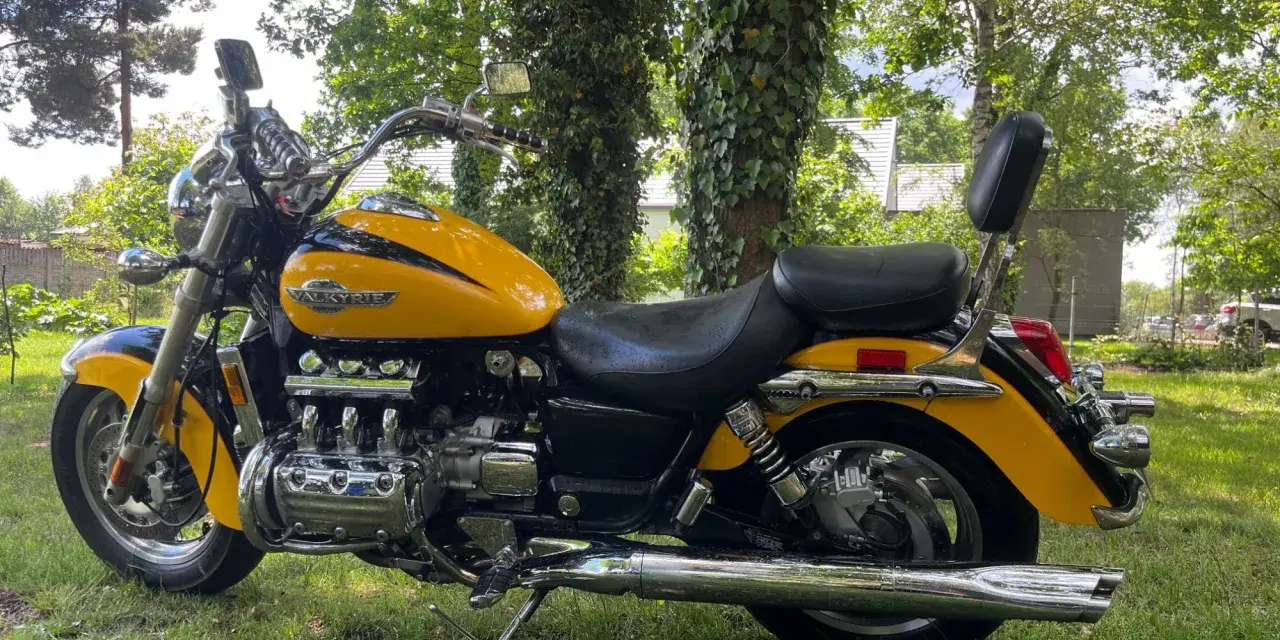 Żółta Honda Valkyrie 1500, z chromowanymi elementami i potężnym silnikiem, zaparkowana na trawie. Dane techniczne tego klasyka budzą podziw.