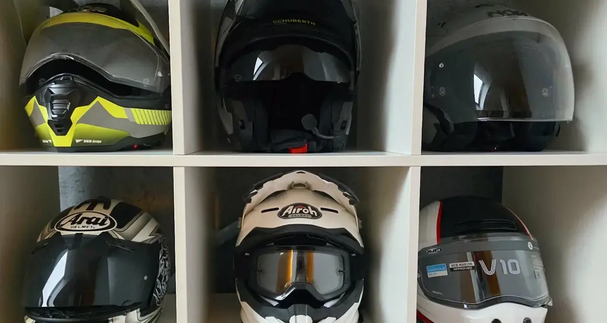 Sześć kasków motocyklowych w różnych kolorach i stylach, ułożonych w sześciu przegrodach.