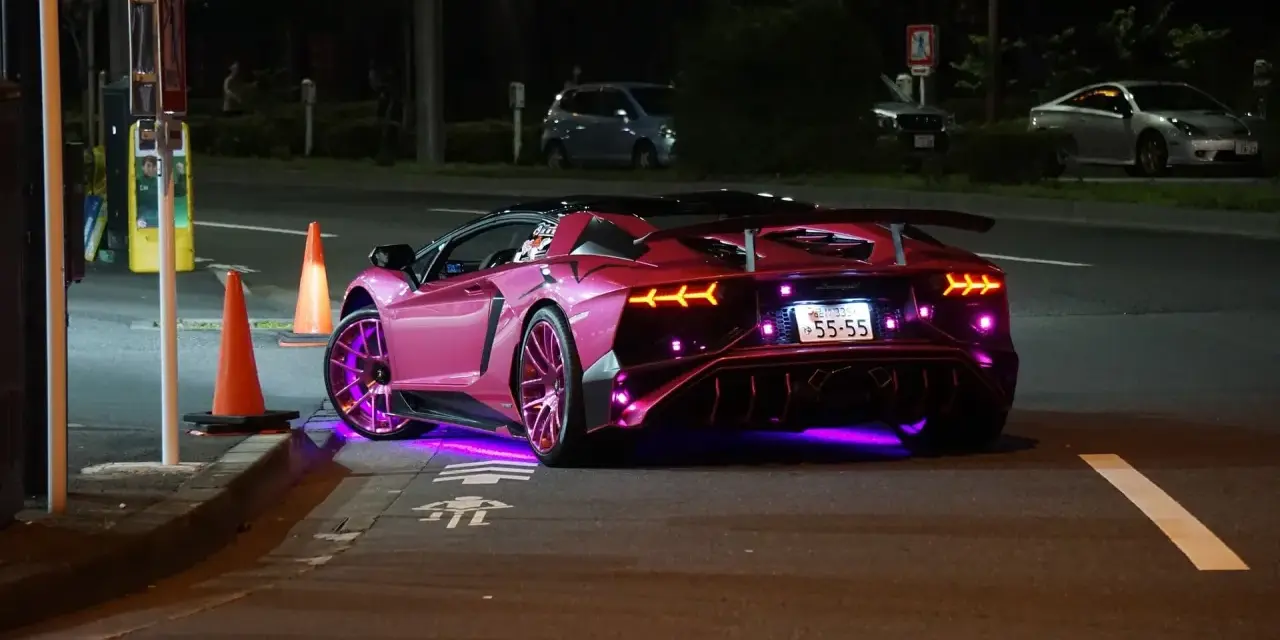Różowy Lamborghini z neonowym podświetleniem na ulicy nocą.