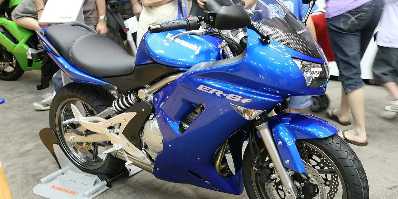 Błękitny motocykl Kawasaki ER-6f, z widocznymi danymi technicznymi na owiewce, prezentowany na wystawie.