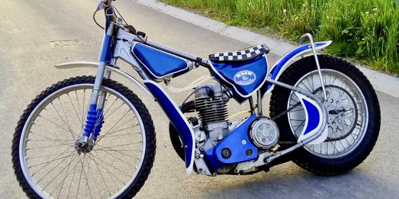 Niebieski motor żużlowy na asfalcie. Zastanawiasz się, ile kosztuje motor żużlowy? Ten wygląda na gotowy do startu!