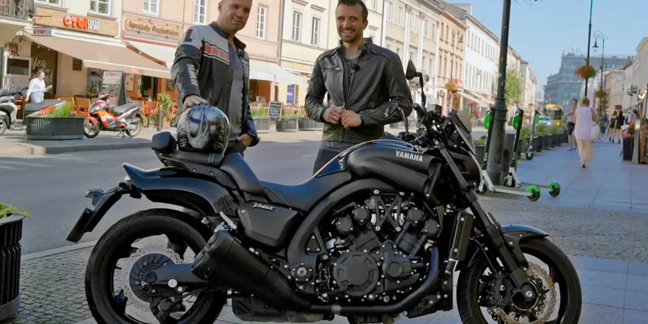 Dwóch mężczyzn pozuje obok czarnego motocykla Yamaha V-Max 1700 na ulicy.