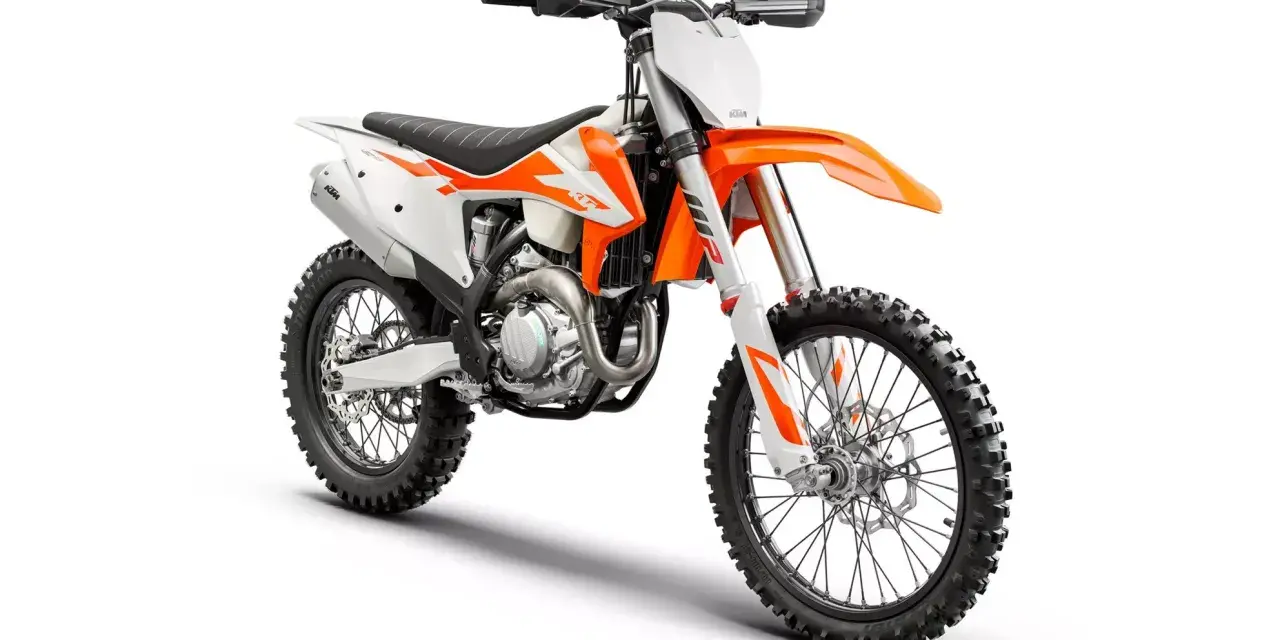 Pomarańczowo-biały motocykl KTM EXC 450, gotowy na teren. Poznaj jego dane techniczne i poczuj moc!