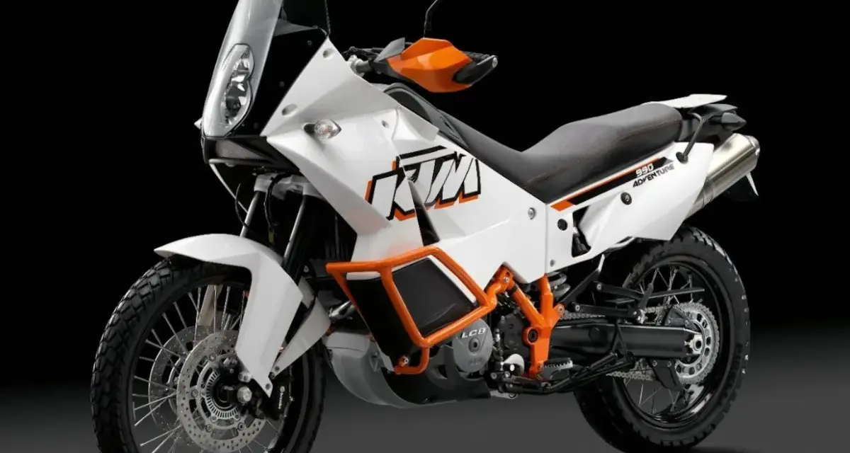 Biały motocykl KTM 990 Adventure z pomarańczowymi akcentami, gotowy na każdą przygodę.