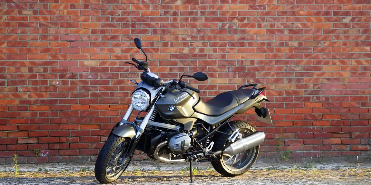 Szary motocykl BMW R1200R na tle ceglanej ściany. Poznaj jego dane techniczne i możliwości.