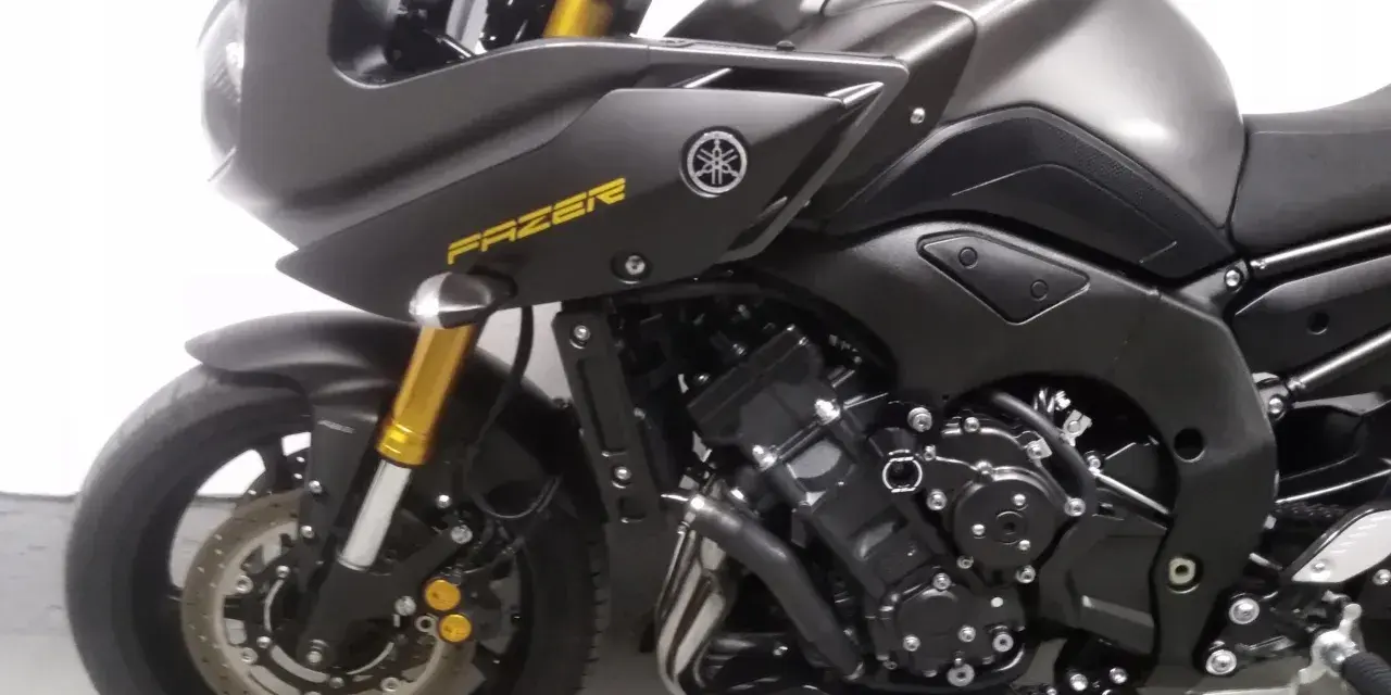 Ciemnoszary motocykl Yamaha FZ8 z żółtym napisem "FAZER" na owiewce. Widoczny silnik i przednie zawieszenie.