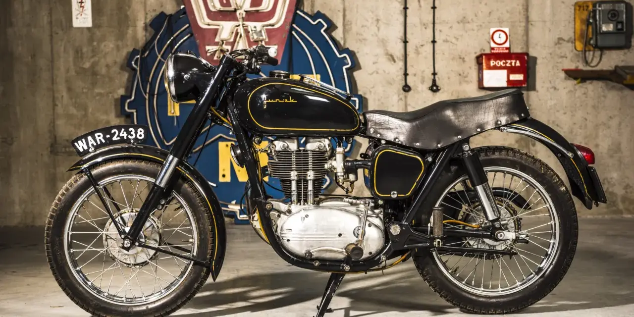 Czarny motocykl Junak, który produkuje polska fabryka, z żółtymi wstawkami i tablicą rejestracyjną WAR-2438.