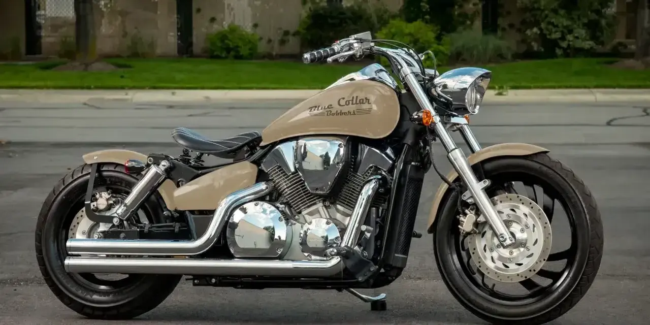 Beżowy motocykl Honda VTX 1300 z chromowanymi elementami i czarnym siedzeniem, zaparkowany na ulicy.