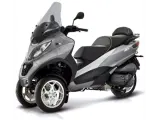 Srebrny Piaggio MP3 400 czy 500? Trójkołowy skuter z przyciemnianą szybą i sportowym designem.
