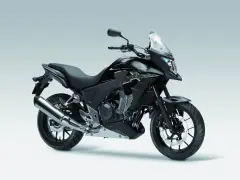 Czarny motocykl Honda CB500X z przyciemnianą szybą i srebrnym wydechem, gotowy na przygodę.