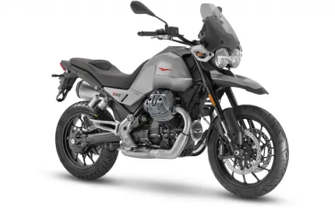 Srebrny motocykl Moto Guzzi V85 TT z czarnym siedzeniem i przyciemnianą szybą, gotowy na przygodę.