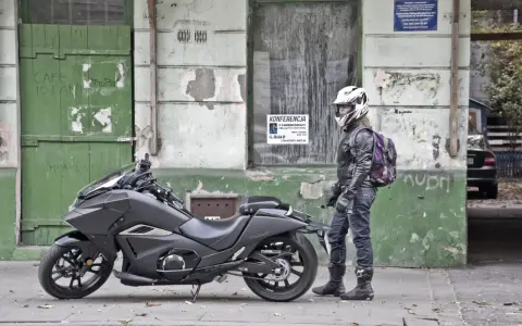 Motocyklista w kasku obok swojego futurystycznego Honda NM4 Vultus.