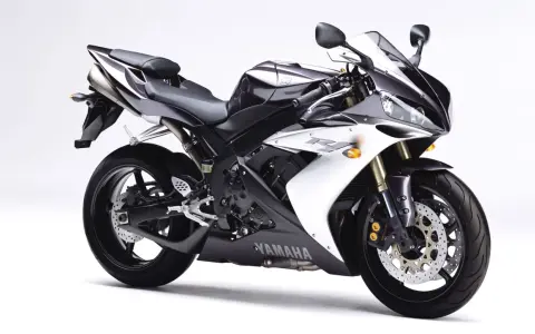 Sportowy motocykl Yamaha R1, jedna z wielu generacji, w kolorze czarno-białym, prezentuje się dynamicznie na białym tle.