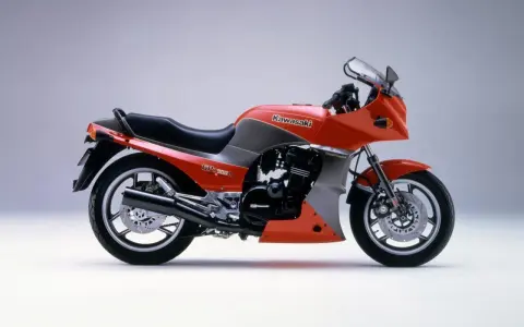 Pomarańczowy motocykl Kawasaki GPZ900R z szarymi akcentami, z lat 80., z owiewką i sportowym wyglądem.