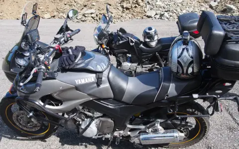 Dwa motocykle Yamaha zaparkowane na drodze szutrowej, jeden z kaskiem na siedzeniu.
