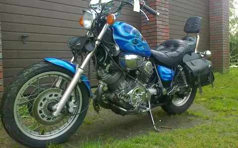 Błękitny motocykl Yamaha Virago 1100 z płomieniami, skórzanymi sakwami i oparciem. Wady i zalety tego klasyka do rozważenia przed zakupem.
