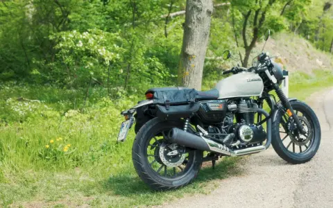 Stojący na poboczu, w otoczeniu zieleni, motocykl Honda GB350 z sakwami gotowy na podróż.
