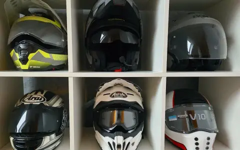 Sześć kasków motocyklowych w różnych kolorach i stylach, ułożonych w sześciu przegrodach.