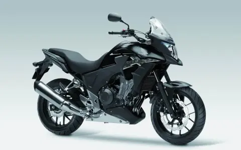 Czarny motocykl Honda CB500X z przyciemnianą szybą i srebrnym wydechem, gotowy na przygodę.
