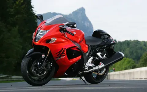 Czerwony motocykl Suzuki Hayabusa na drodze, z widokiem na góry. Poznaj jego suzuki hayabusa dane techniczne.