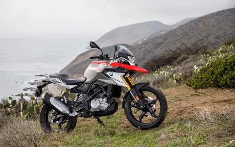 BMW G 310 GS na tle górskiego krajobrazu z widokiem na ocean. Poznaj jego dane techniczne i możliwości terenowe.
