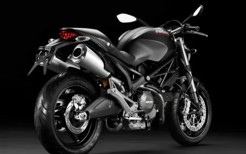 Czarny Ducati Monster 696 z podwójnym wydechem i sportowym wyglądem, gotowy do jazdy.