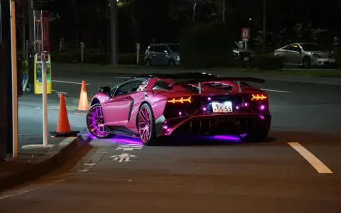 Różowy Lamborghini z neonowym podświetleniem na ulicy nocą.