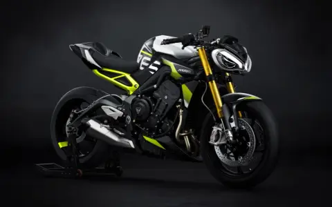 Agresywny Triumph Street Triple w biało-czarnej kolorystyce z neonowo-żółtymi akcentami, zdominowany przez złote lagi i sportowy wygląd.