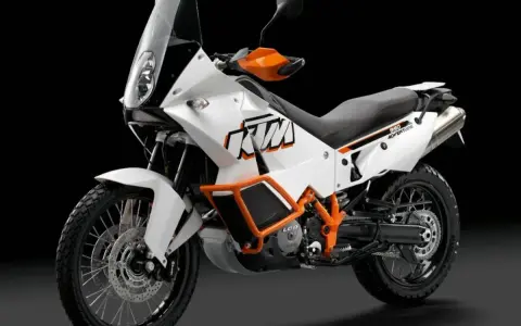 Biały motocykl KTM 990 Adventure z pomarańczowymi akcentami, gotowy na każdą przygodę.